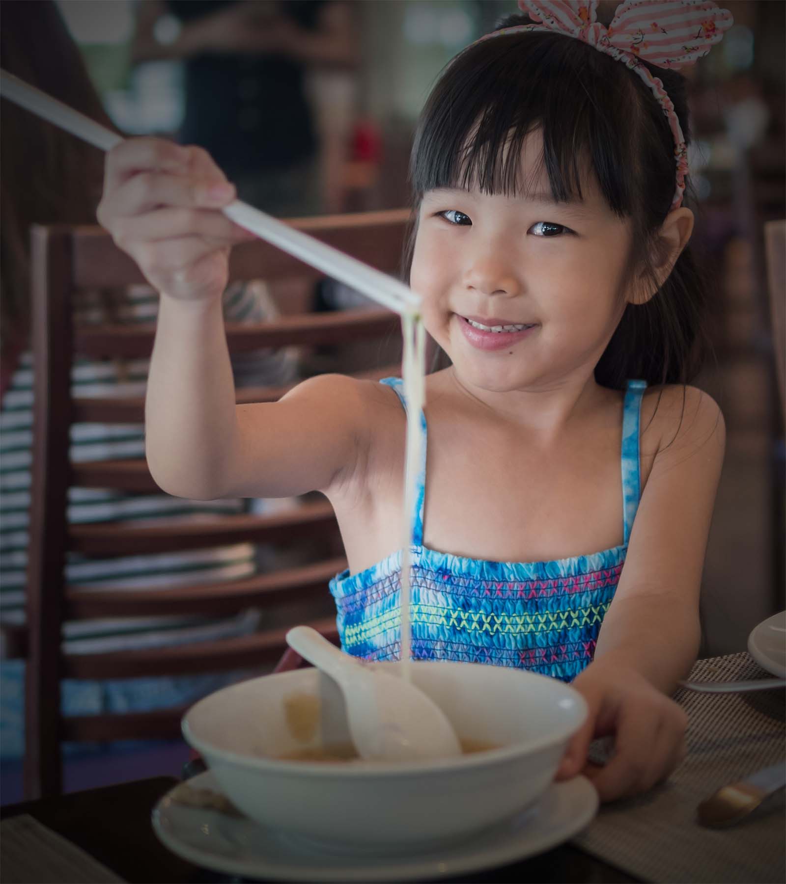 Happy Asian child eating delicious noodle with chopstick, in the Happy Asian child eating delicious noodle with chopstick, in the